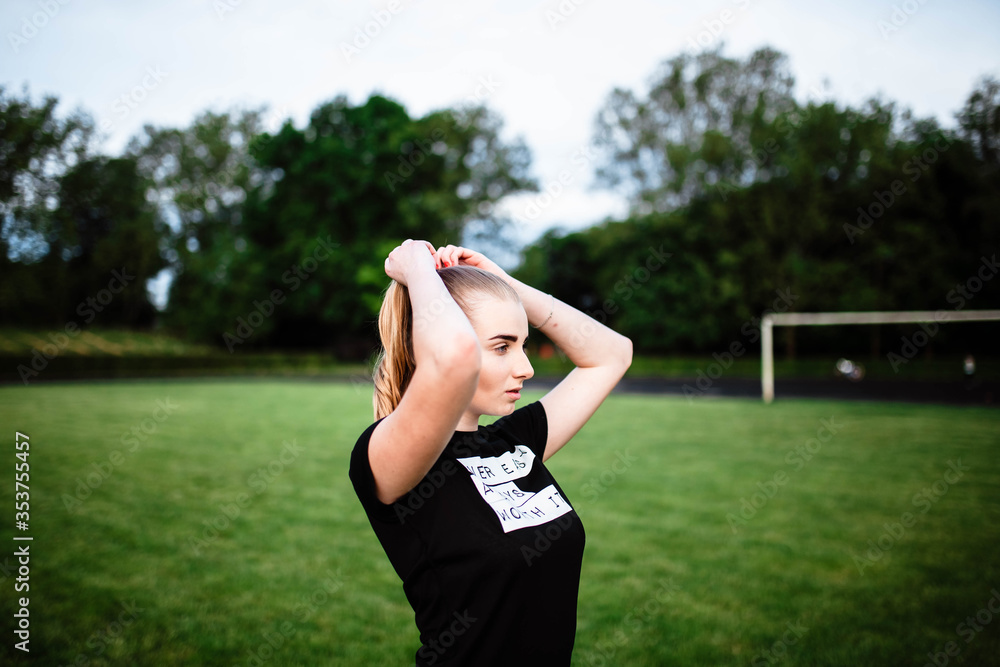 Healthy sports lifestyle. Athletic young woman in a sports dress doing fitness exercises. Fitness woman at the stadium. The young girl goes in for sports. A young girl makes a ponytail. Healthy sports lifestyle. Athletic young woman in a sports dress doing fitness exercises. Fitness woman at the stadium. The young girl goes in for sports. A young girl makes a ponytail.