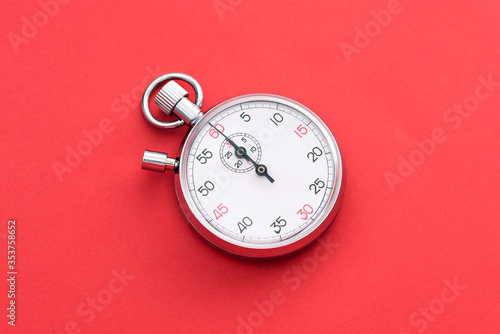 Analogue metal stopwatch on the red background.