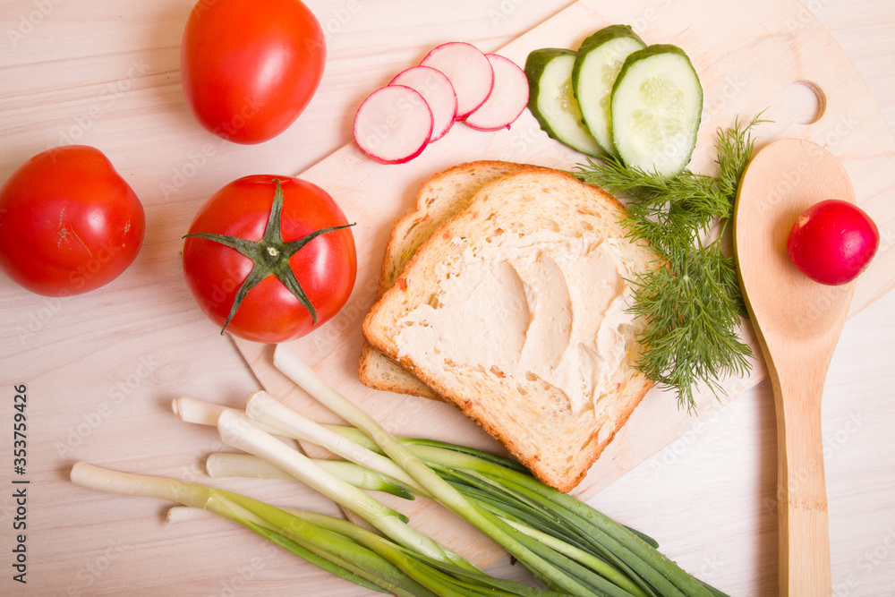 a piece of bread spread with hummus, vegetables and dill on a wooden table, ingredients for a vegan sandwich, healthy and tasty breakfast concept a piece of bread spread with hummus, vegetables and dill on a wooden table, ingredients for a vegan sandwich, healthy and tasty breakfast concept
