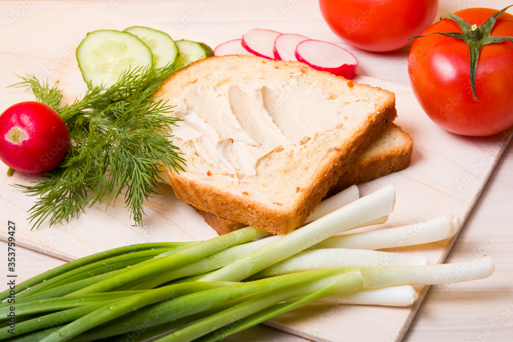 a piece of bread spread with hummus, vegetables and dill on a wooden table, ingredients for a vegan sandwich, healthy and tasty breakfast concept a piece of bread spread with hummus, vegetables and dill on a wooden table, ingredients for a vegan sandwich, healthy and tasty breakfast concept