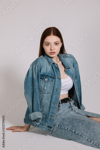 Girl in jeans and red sneakers posing on a white background