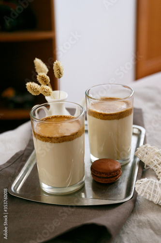 Dalgon coffee in two glass glasses. Milk coffee in bed. Milk with coffee foam in glasses