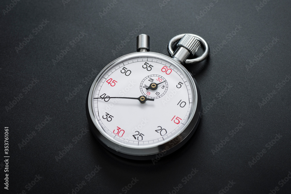 Analogue metal stopwatch on the black background.