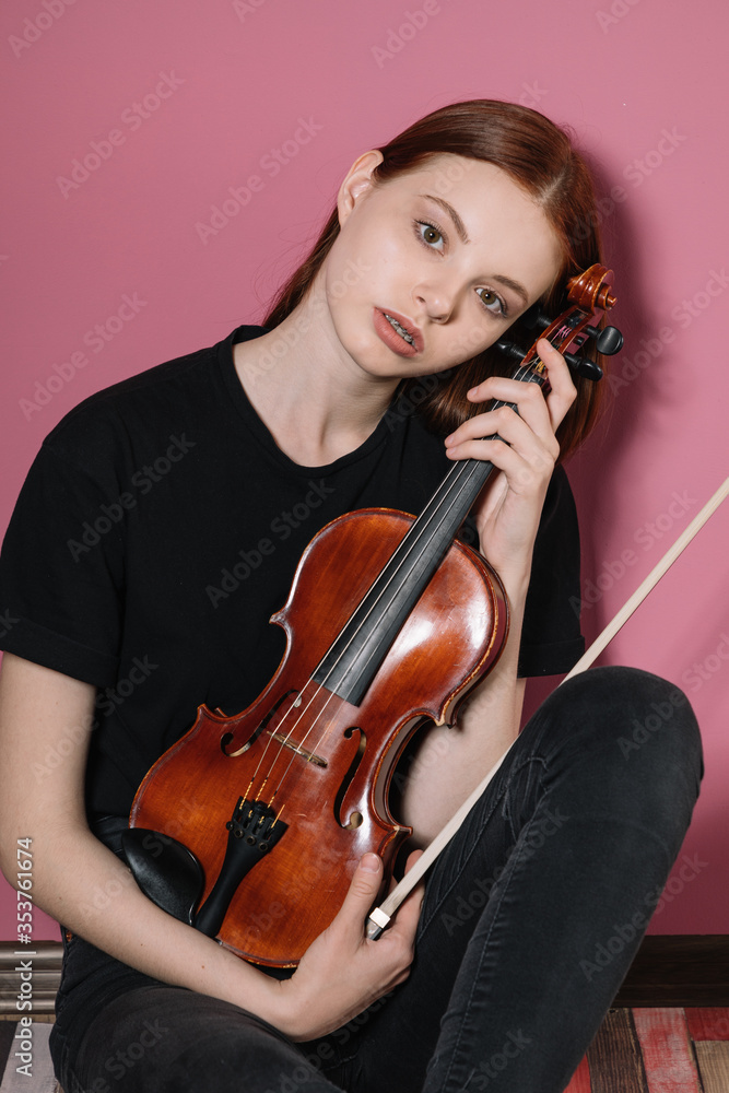 Girl in black plays violin on pink background Girl in black plays violin on pink background