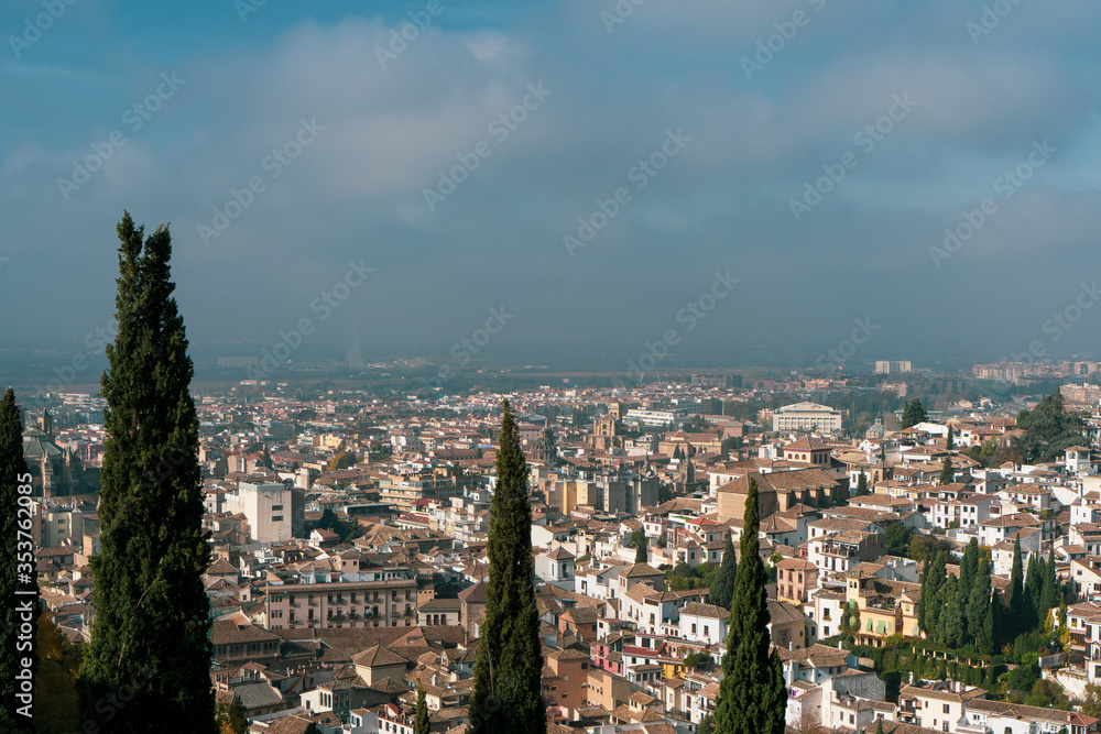 Fototapeta premium Beautiful landscape of Granada, Spain. Blue sky, tall trees and charming buildings from above. 