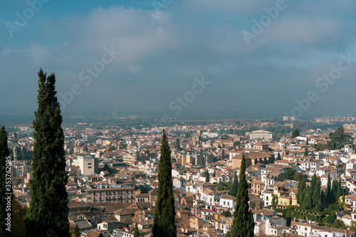 Beautiful landscape of Granada, Spain. Blue sky, tall trees and charming buildings from above. 