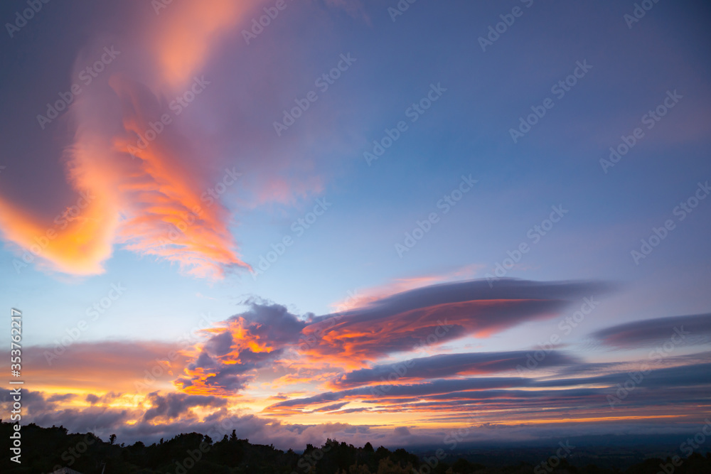 Bright pink and shades of intensity of sunset colored sky over wide landscape below