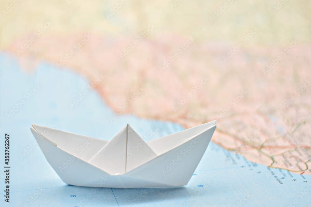 Barco de papel sobre un mapa del mundo difuminado Stock Photo | Adobe Stock