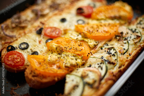 Long baguettes pizza sandwiches with tuna, mushrooms, tomatoes and cheese on a metal baking tray