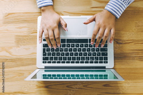 Topview shot of business person using laptop with green screen at a wooden table.