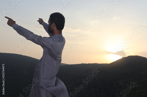 young man standing in the mountains with arms out stretched