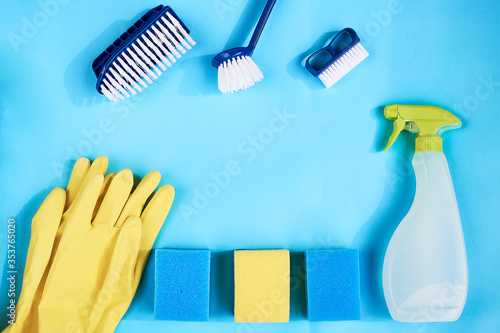 Blue dish brushes, yellow gloves and cleaning rag on a blue background. Space for text