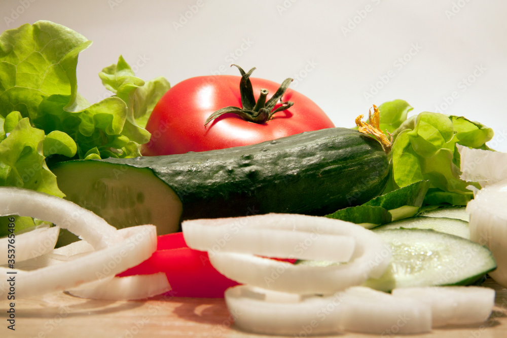 tomato cucumbers onions and lettuce closeup on a white background