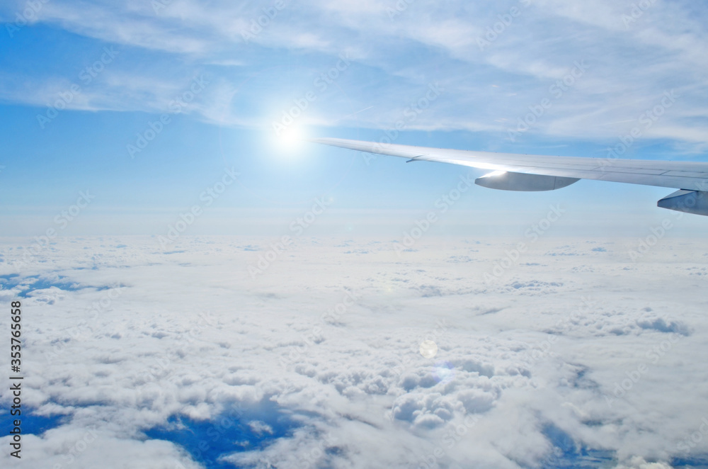 Airplane wing out of window, flying above the morning clouds Airplane wing out of window, flying above the morning clouds