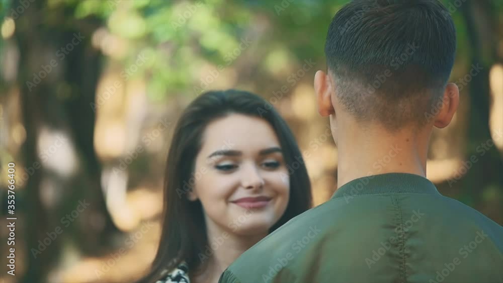 Adorable girl is coming closer and hugs her boyfriend in the park. Close up. Copy space. 4K. Adorable girl is coming closer and hugs her boyfriend in the park. Close up. Copy space. 4K.