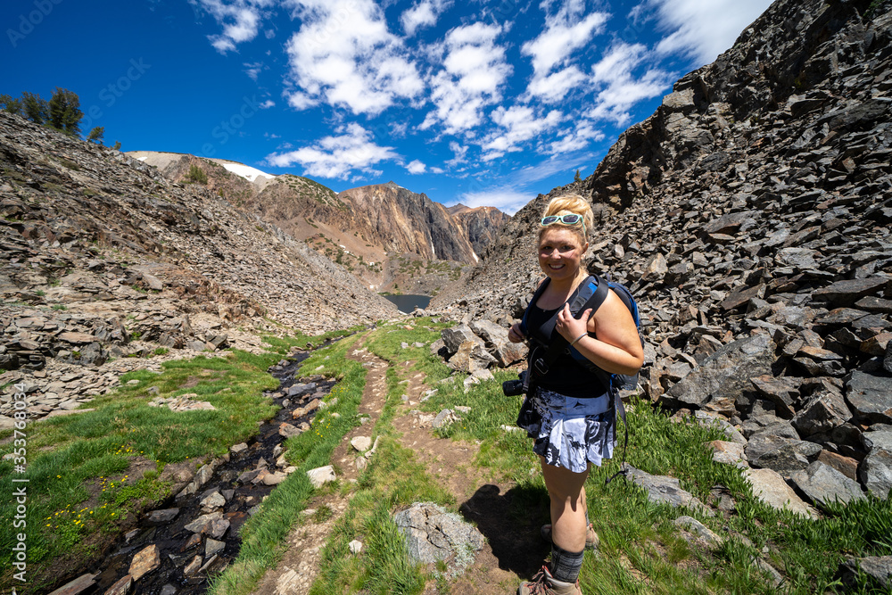 Young adult woman hiker walks along the dirt path through the mountains in Eastern Sierra California, 20 Lakes Basin trail