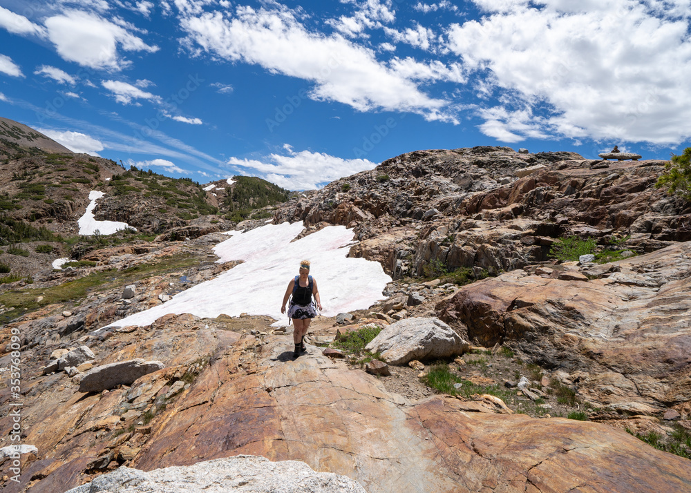 Dejected, injured female hiker walks along the 20 Lakes Basin after hiking through a snow field in summer. Mono County, California
