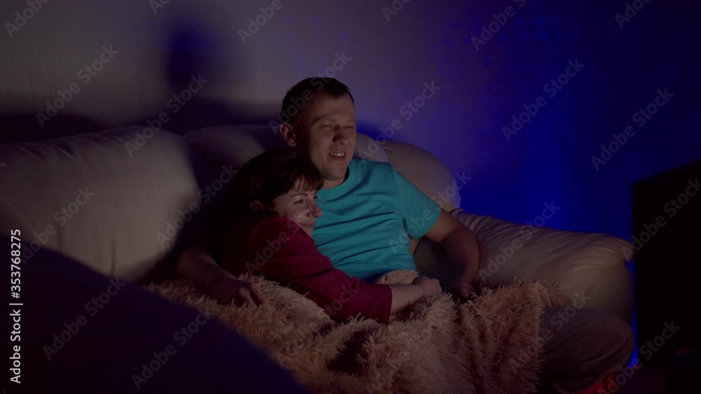 Married couple sitting embracing late at night and watching TV Married couple sitting embracing late at night and watching TV