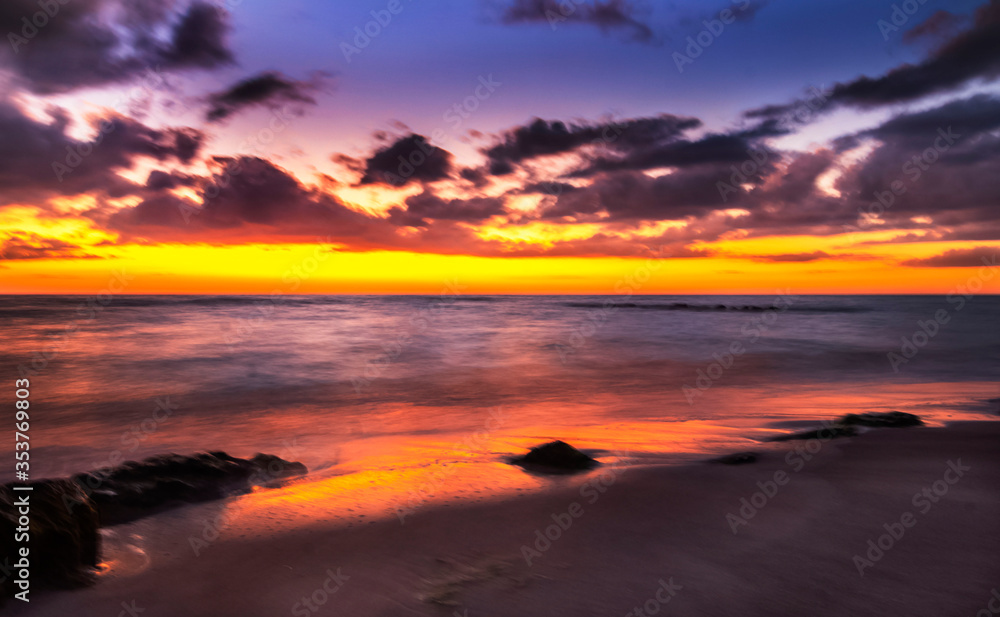 Obraz premium sunset over the sea, sky, water, beach, ocean, orange, rocks, clouds, blue, waves, reflection yellow, sundown