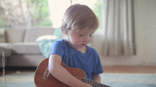 Young Caucasian boy learns to play ukulele or guitar. 