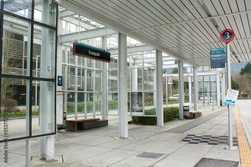 Empty bus stop shelter with glass walls, roof and benches.