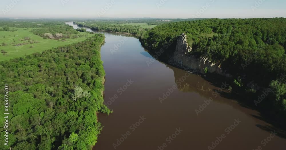 Alone rock on wide dirty river with green forest coast, forest. Aerial drone wide shot at summer sunny day. Alone rock on wide dirty river with green forest coast, forest. Aerial drone wide shot at summer sunny day.