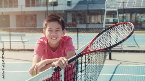 Young healthy and happy tween preteen mixed Asian boy tennis beginner player on outdoor blue court, active child sport, student school camp © SewcreamStudio