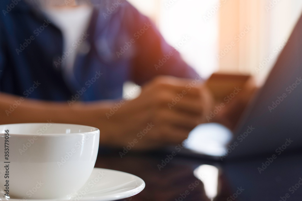 Blurred image of casual man hand make online payment, pay bill and internet banking by using debit or credit card and laptop computer. e business, internet banking concept. Flare light. Blurred image of casual man hand make online payment, pay bill and internet banking by using debit or credit card and laptop computer. e business, internet banking concept. Flare light.