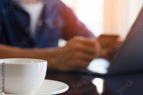 Blurred image of casual man hand make online payment  pay bill and internet banking by using debit or credit card and laptop computer. e business  internet banking concept. Flare light.