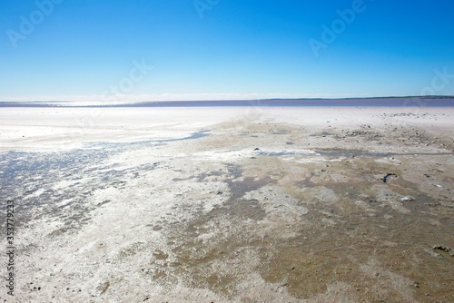 Panoramic landscape view of scenic salt lake in outback desert of Western Australia, with sunny glare, blue sky and horizon as background and copy space.