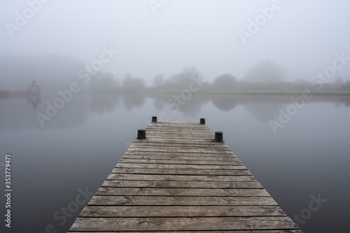 wooden pier at lake on misty autumn day