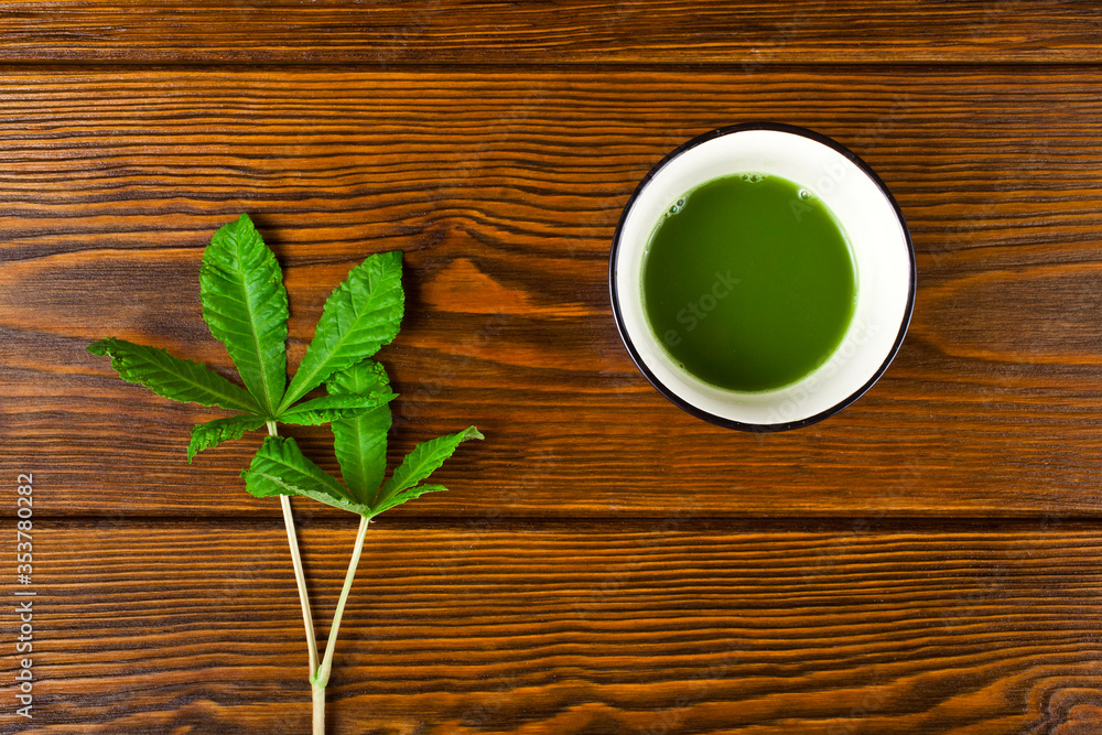 Matcha tea in a cup and green leaves on a wooden background. Top view. Matcha tea in a cup and green leaves on a wooden background. Top view.
