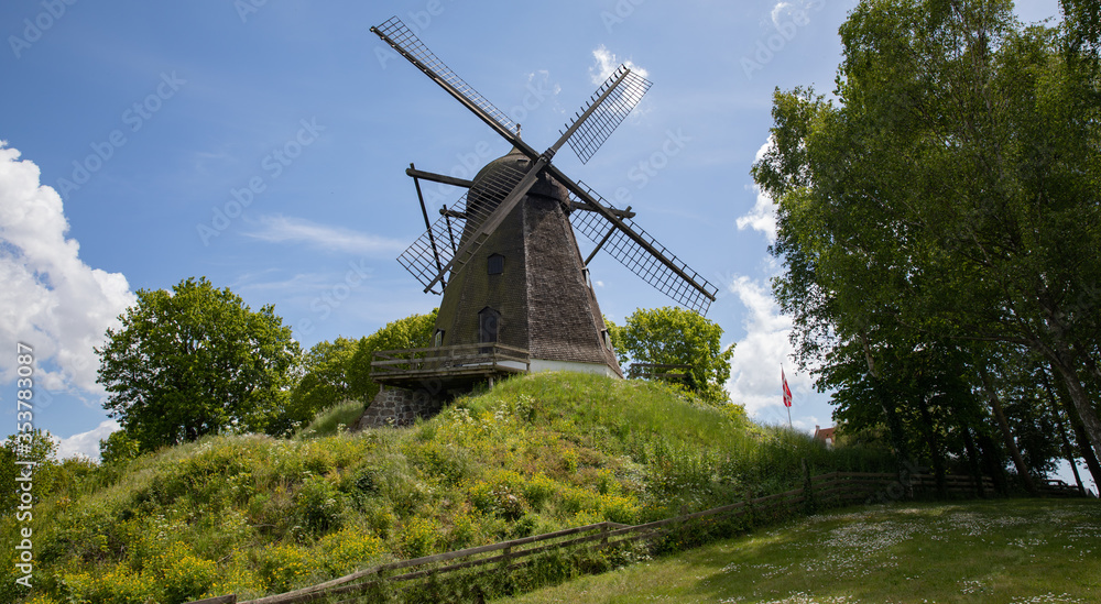Old windmill on a hill with blue sky and clouds