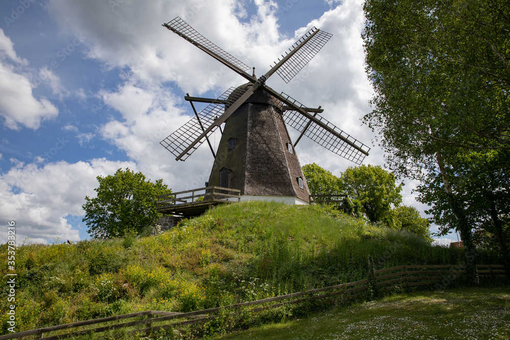 Obraz premium Old windmill on a hill with blue sky and clouds