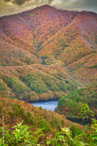 view of autumn mountain in fukushima with blue lake in the center of hill photo