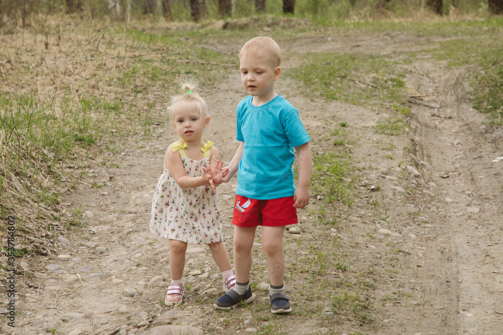 Brother and sister walk along the forest road Brother and sister walk along the forest road