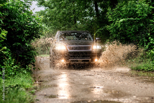 black suv car crossing wet mountain road.