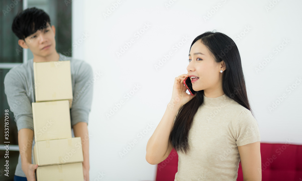 Asian woman customer from online shopping calling to order and delivery package in living room Asian woman customer from online shopping calling to order and delivery package in living room