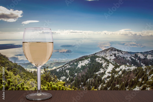 Glass of white wine with view of mountains and sea and blue sky with clouds in Croatia