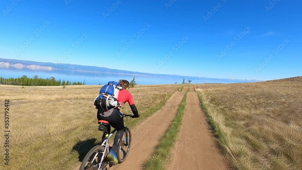 Young sports man riding bicycle at the rural road over field. Sporty guy cycling along country trail outdoor. Male cyclist riding bike in the countryside. Healthy active lifestyle Slow motion Young sports man riding bicycle at the rural road over field. Sporty guy cycling along country trail outdoor. Male cyclist riding bike in the countryside. Healthy active lifestyle Slow motion