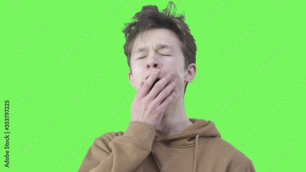 Close-up of tired boy yawning. Portrait of exhausted college student posing at green background. Exhaustion, tiredness, overworking, studying. Chromakey. Close-up of tired boy yawning. Portrait of exhausted college student posing at green background. Exhaustion, tiredness, overworking, studying. Chromakey.