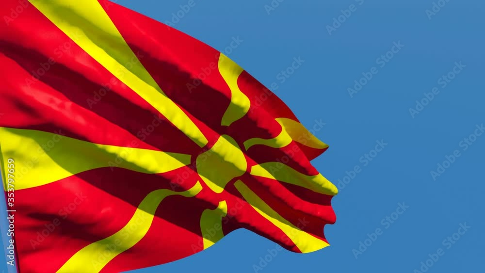 The national flag of Macedonia flutters in the wind against a blue sky The national flag of Macedonia flutters in the wind against a blue sky