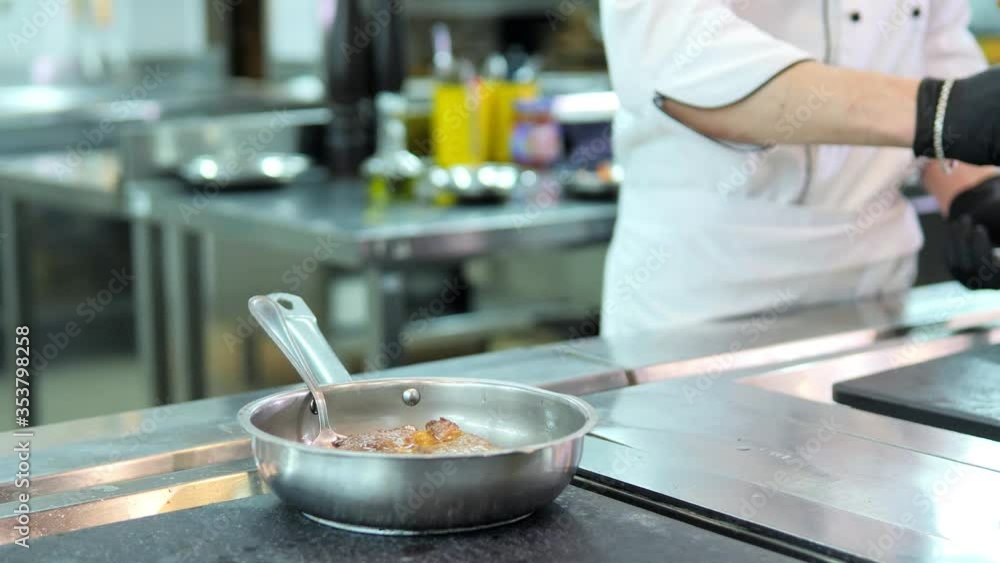 Chef in protective masks and gloves prepares food in the kitchen of a restaurant or hotel Chef in protective masks and gloves prepares food in the kitchen of a restaurant or hotel