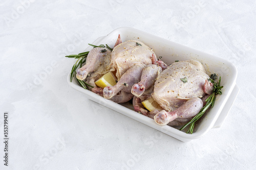 raw coquelet chickens prepared for roasting with vegetables and herbs photo