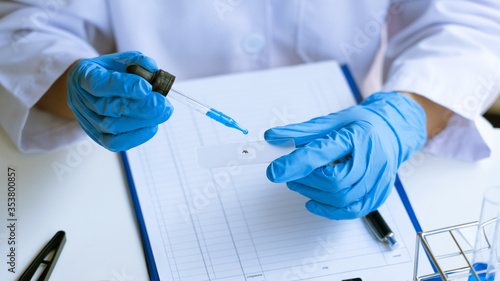 scientists researching in laboratory in white lab coat, gloves analysing, looking at test tubes sample, biotechnology concept