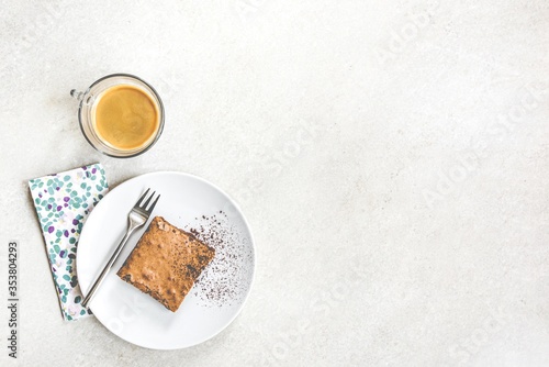 Obraz na płótnie Top view of a cup of coffee and a dessert plate with brownie cake over white rustic background. w salonie