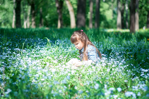 Portrait of a beautiful girlsitting in forget me not blue flowers