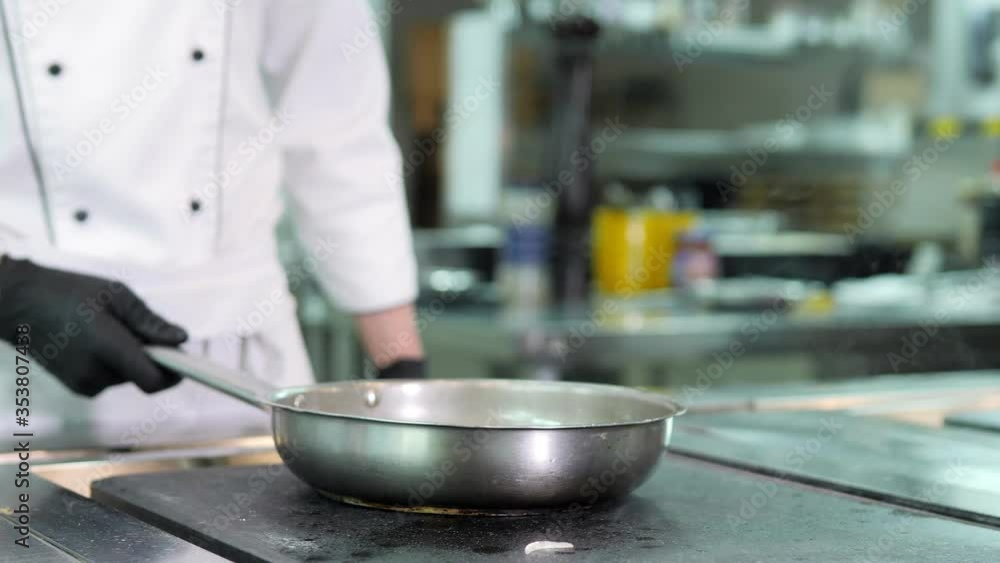 Chef in protective masks and gloves prepares food in the kitchen of a restaurant or hotel Chef in protective masks and gloves prepares food in the kitchen of a restaurant or hotel
