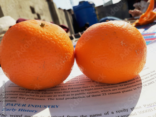 Islamabad,Pakistan-February 06,2020: Fresh orange fruit is placed on an open book in daylight. Healthy food and diet,background and textured. photo