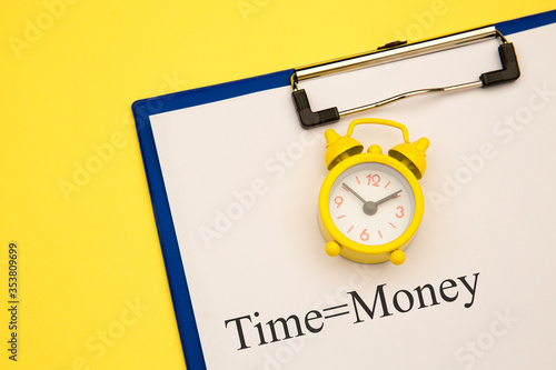 Time is money concept with alarm clock aside on yellow background. photo